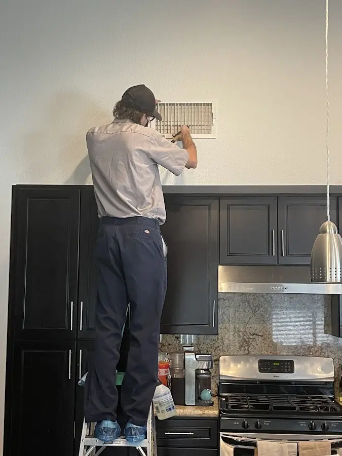 Technician inspecting an air vent during HVAC service in Eagle Point
